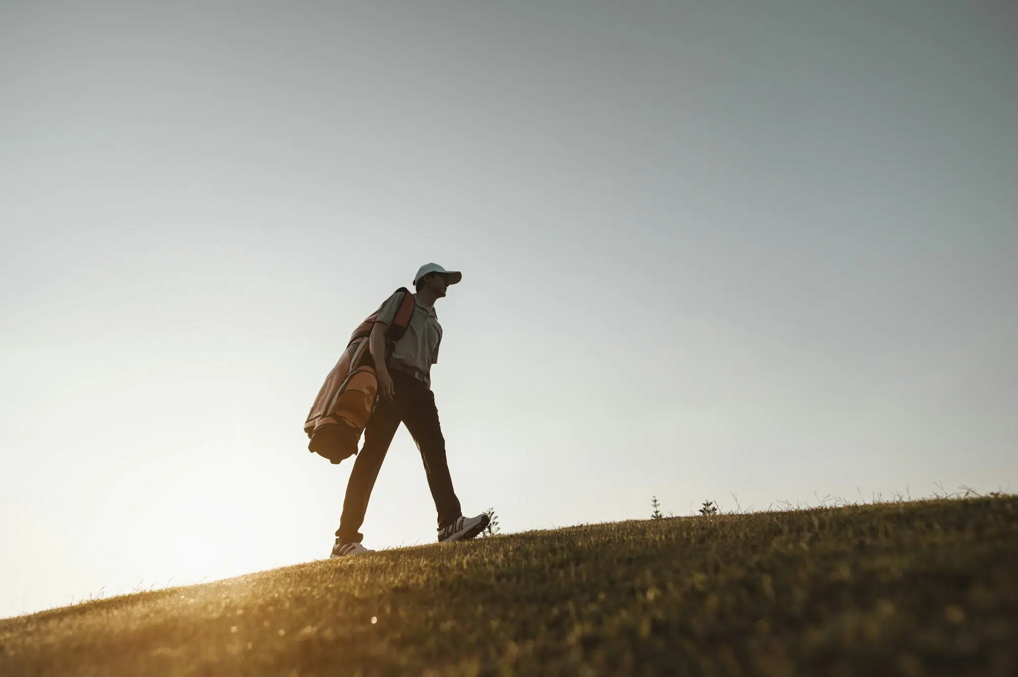 lifestyle, golf, activity, sport, golfer concept A man is carrying a golf bag on a hill at a golf